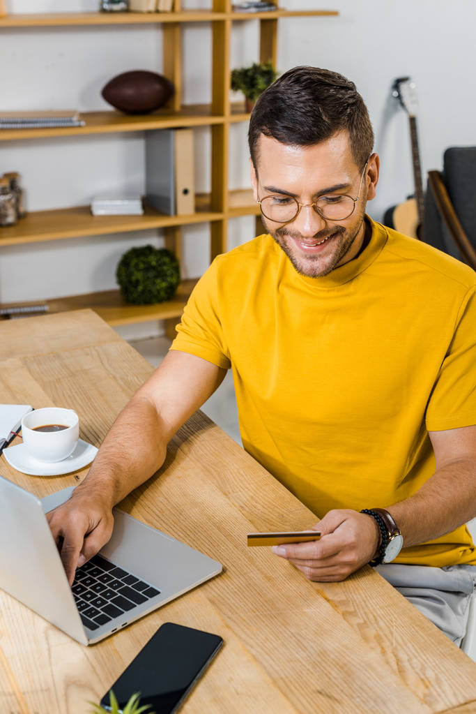 handsome man looking at credit card while using laptop  - Photo, Image