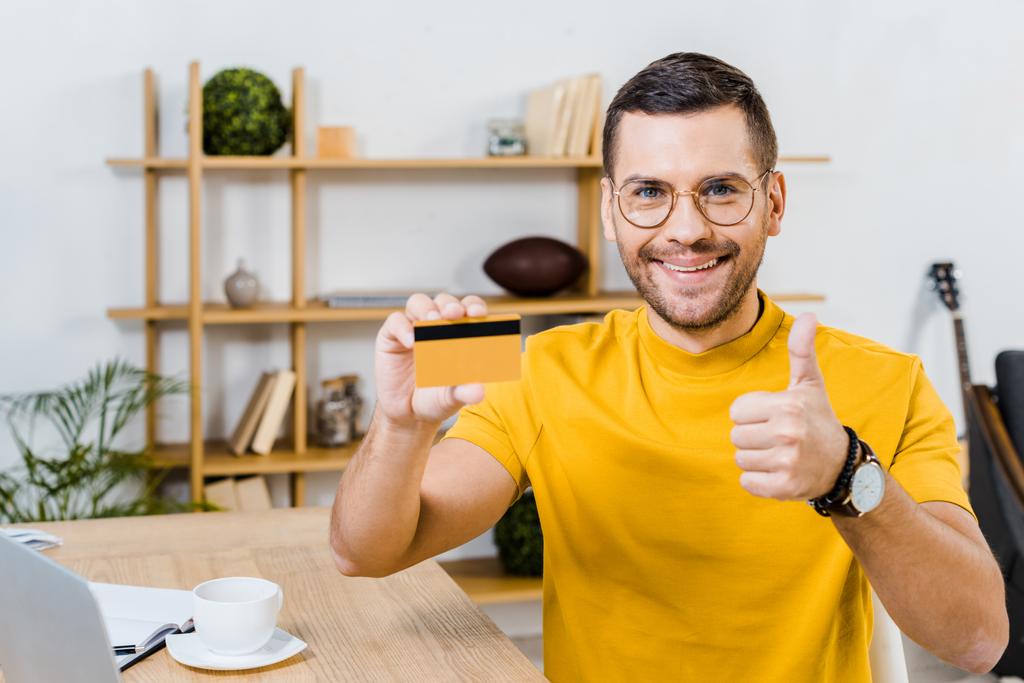 handsome man showing thumb up while holding credit card  - Photo, Image