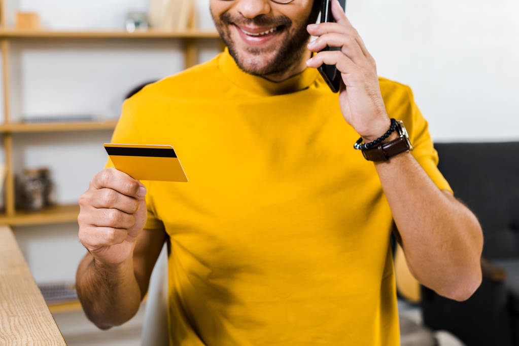 rajattu näkymä mies puhuu älypuhelimella ja tilalla luottokortti
 - Valokuva, kuva