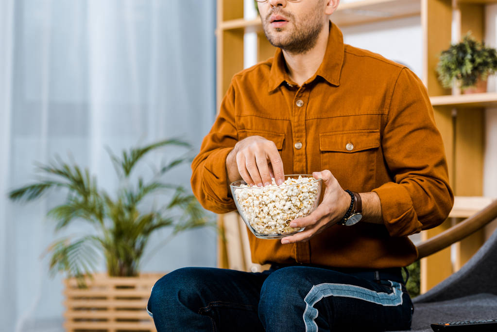 przycięte widzenia zaskoczony mężczyznę trzymającego popcorn miski - Zdjęcie, obraz