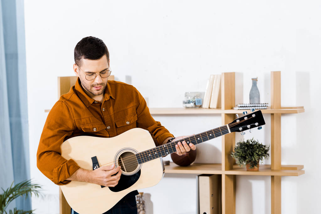 schöner Musiker, der zu Hause Akustikgitarre spielt - Foto, Bild