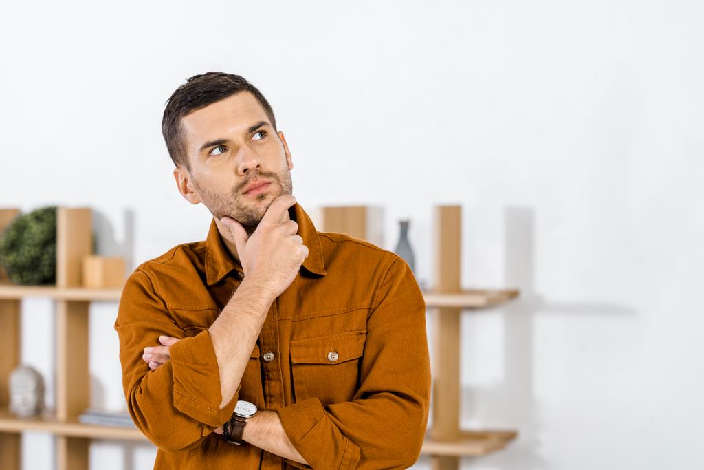 handsome man standing in modern living room doing thinking gesture - Photo, Image