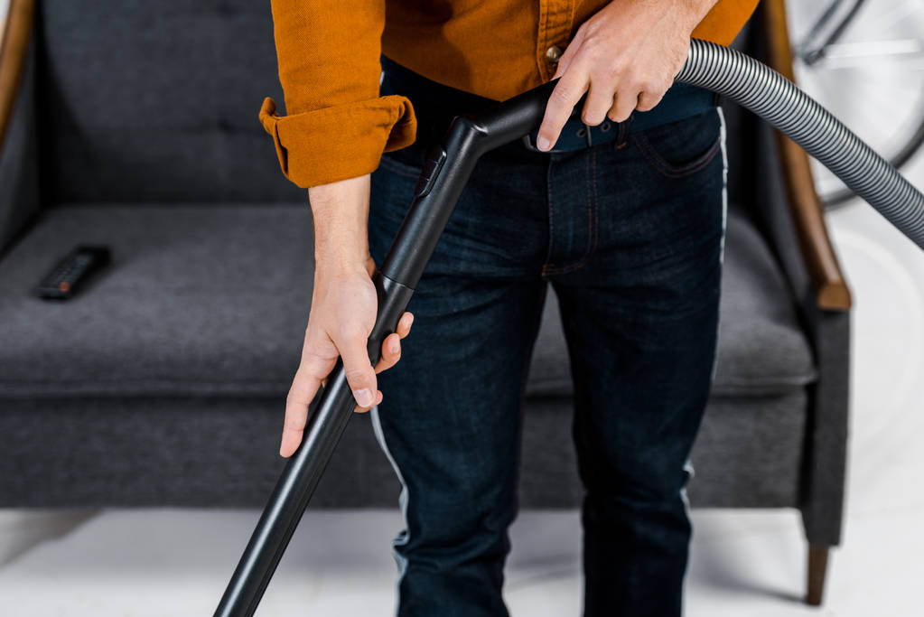 oříznutý pohled člověka v moderní bydlení čištění podlahy s hoover - Fotografie, Obrázek