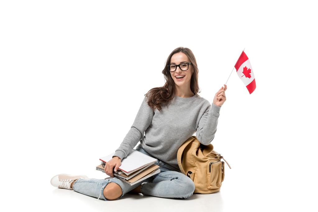 счастливая студентка, сидящая с канадским флагом и блокнотами, изолированными на белом
 - Фото, изображение
