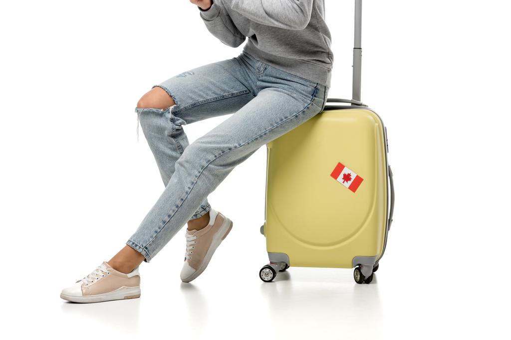 concept bijgesneden beeld van vrouw zittend op koffer met Canadese vlag sticker op wit wordt geïsoleerd, reizen - Foto, afbeelding