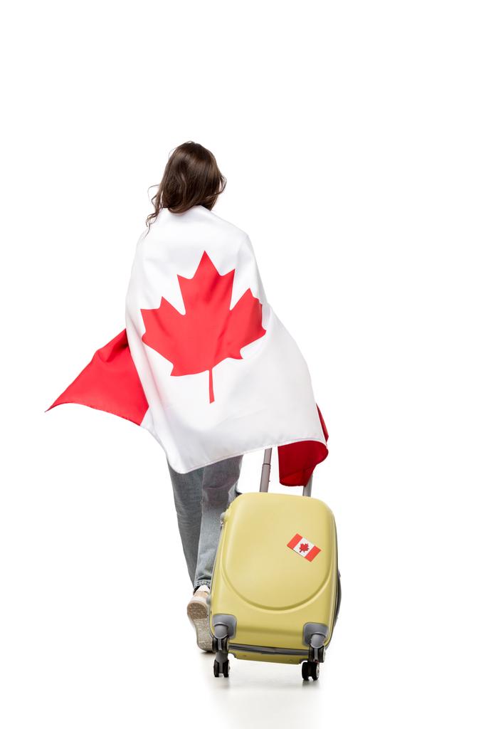 ΠΙΣΩ ΟΨΗ της γυναίκας που καλύπτονται στην καναδική σημαία με βαλίτσα που απομονώνονται σε λευκό, έννοια του ταξιδιού - Φωτογραφία, εικόνα