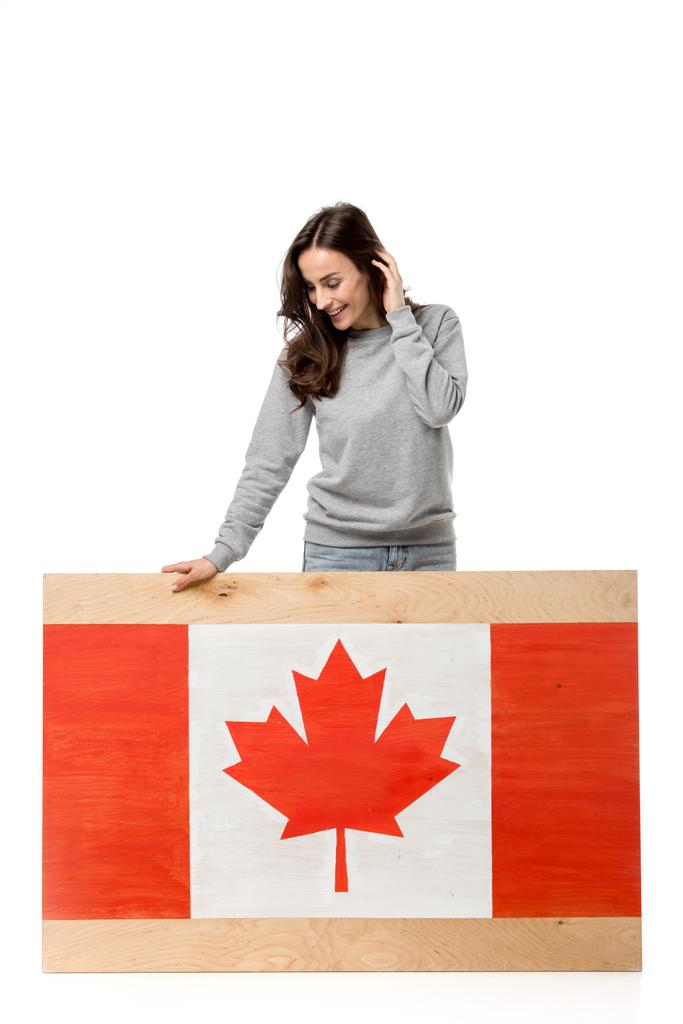 uśmiechający się kobiety stojącej w pobliżu deska z kanadyjską flagę i patrząc od hotelu na białym tle - Zdjęcie, obraz