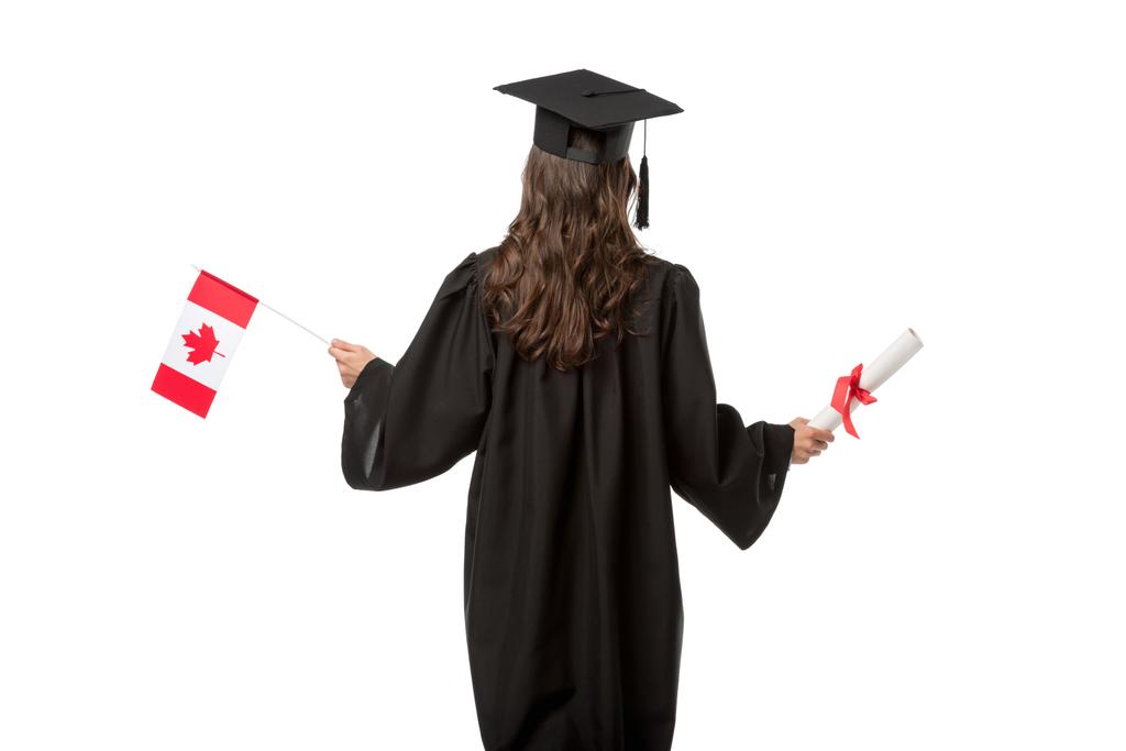 Achteraanzicht van een vrouwelijke student in de academische jurk en mortarboard houden van de Canadese vlag met diploma geïsoleerd op wit - Foto, afbeelding