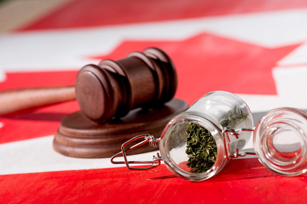 selective focus of cannabis in glass jar with wooden gavel on canadian flag, marijuana legalization concept - Photo, Image