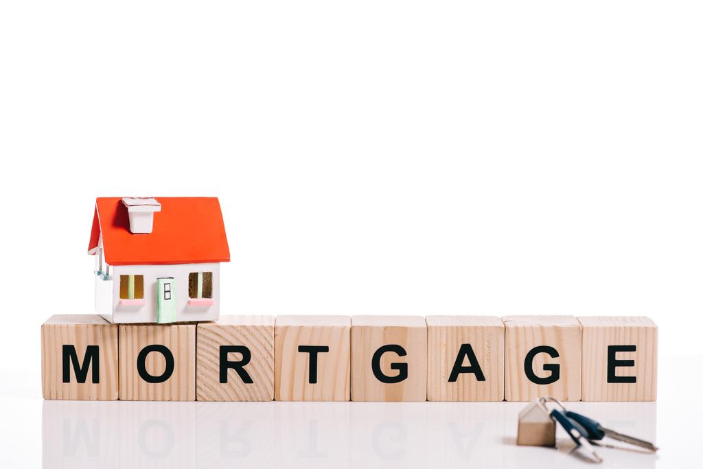Tahta bloklar yazı mortgage ile ev modeli ve anahtarları üzerinde beyaz izole  - Fotoğraf, Görsel