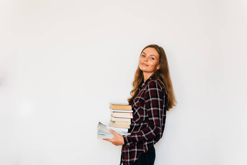 Menina adolescente bonita estudante isolado da escola ou faculdade com pilha de livros
 - Foto, Imagem