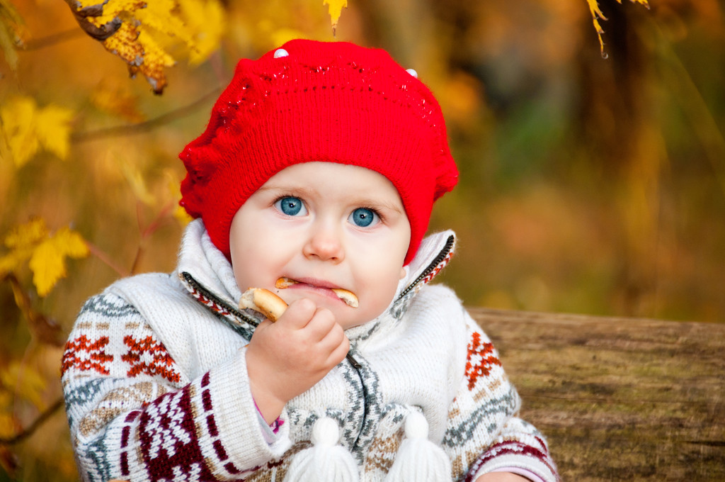 χαριτωμένο μικρό κορίτσι μωρό κάθεται στο δάσος και να τρώει ένα κουλούρι - Φωτογραφία, εικόνα