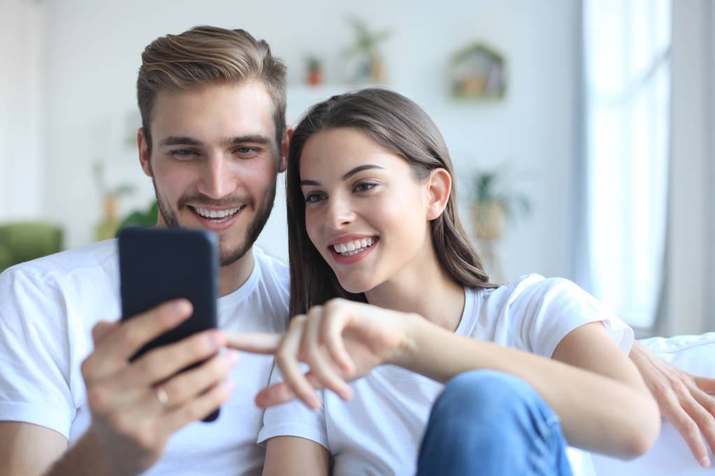 Jovem casal tirando uma selfie no sofá em casa na sala de estar
. - Foto, Imagem