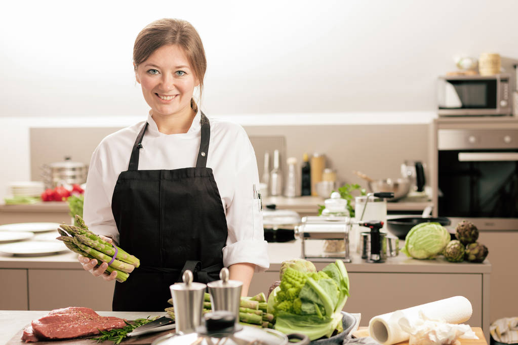 Χαμογελαστή γυναικεία κουζίνα με στολή στέκεται στην κουζίνα στο εστιατόριο. - Φωτογραφία, εικόνα