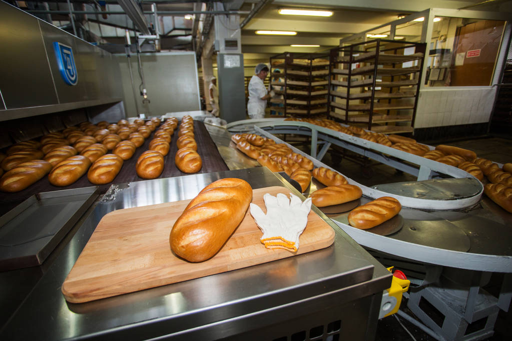 Brotproduktion. weiße Teigsticks werden auf der Linie gebacken. - Foto, Bild