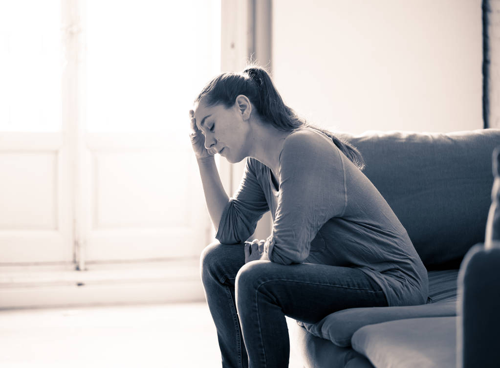 Mujer latina atractiva joven tumbada en el sofá de la sala de estar en casa sintiéndose triste cansado y preocupado sufrimiento Depresión en la salud mental, problemas Dolor emocional y concepto de corazón roto
. - Foto, imagen