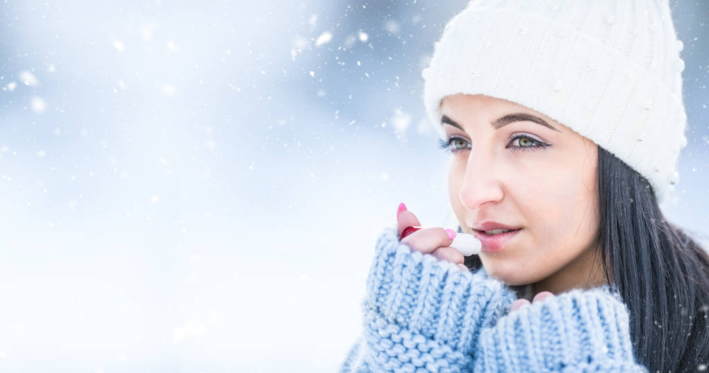 Attrayant jeune femme l protéger les lèvres avec du baume à lèvres par temps neigeux et gelé
. - Photo, image