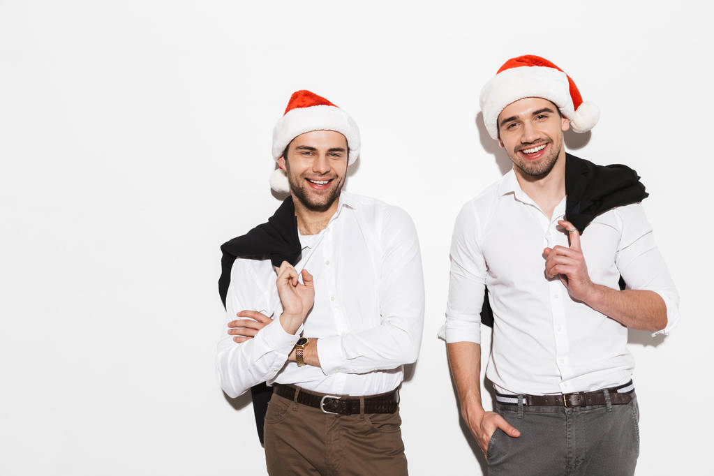 Two cheerful smartly dressed men standing isolated over white background, celebrating New Year - Photo, Image