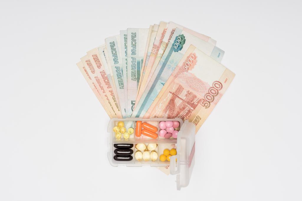 το Top view μετρητά και πλαστικό κουτί με χάπια που απομονώνονται σε γκρι - Φωτογραφία, εικόνα