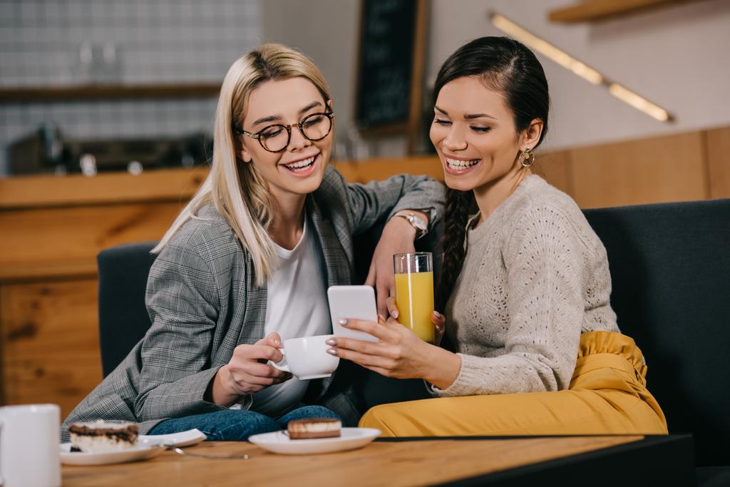mulheres atraentes sorrindo ao tomar selfie no café
 - Foto, Imagem