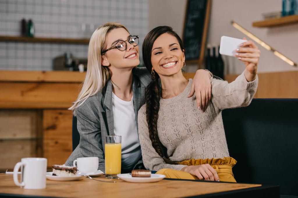 donne felici sorridenti mentre prendono selfie nel caffè
 - Foto, immagini