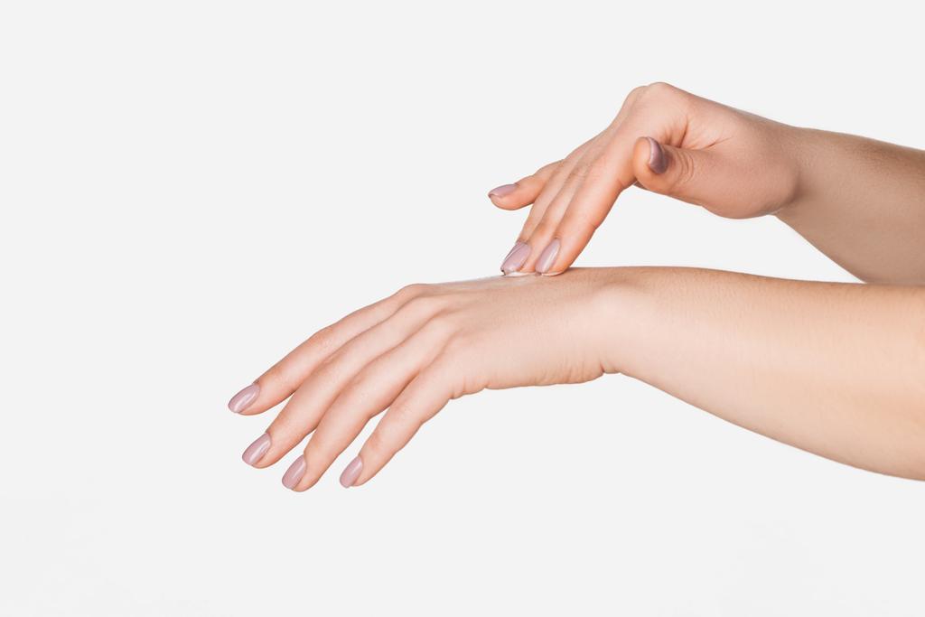 částečný pohled ženy použití hydratační krém na ruce izolované na bílém s kopií prostor - Fotografie, Obrázek