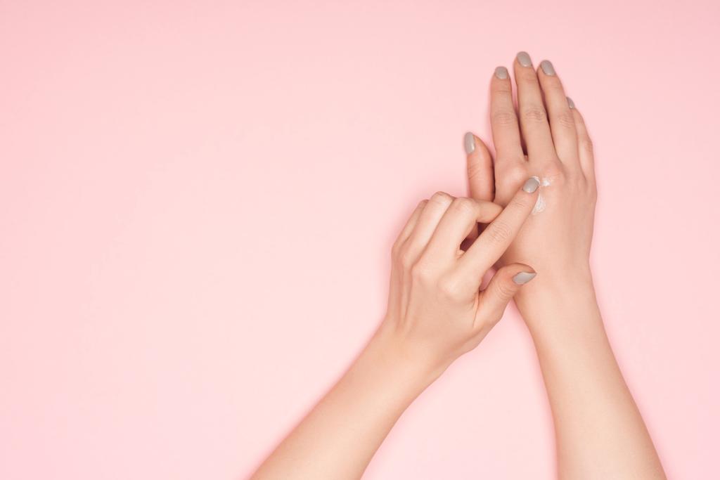 περικοπεί προβολή της γυναίκας εφαρμογή κρέμα χεριών που απομονώνονται σε ροζ - Φωτογραφία, εικόνα
