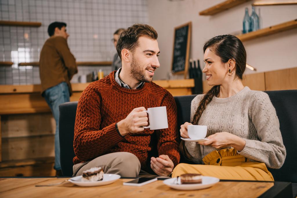 Selektiver Fokus des Paares, das Tassen hält und im Café plaudert - Foto, Bild