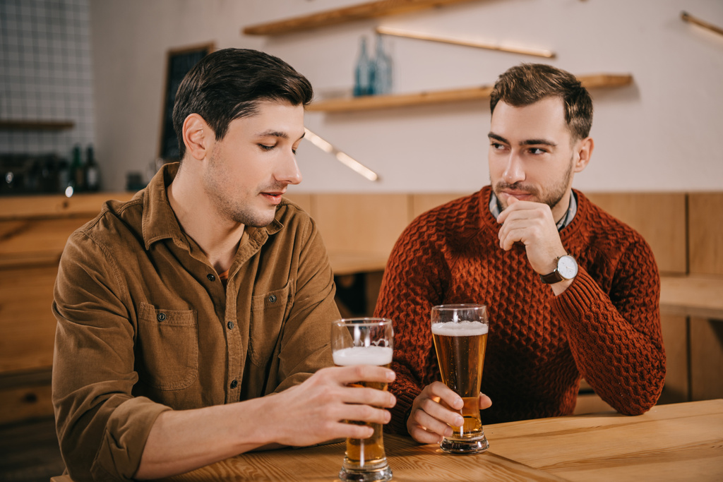 bel homme regardant un verre de bière près d'un ami
 - Photo, image