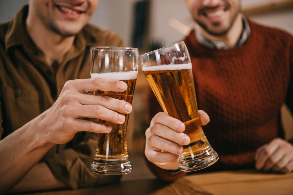 обрезанный вид мужчин, звенящих с пивом в очках
 - Фото, изображение