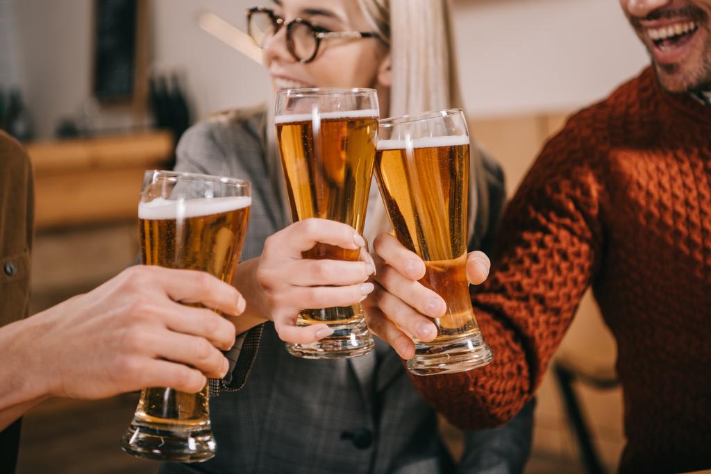 vista cortada de mulher feliz clinking com cerveja com amigos
 - Foto, Imagem
