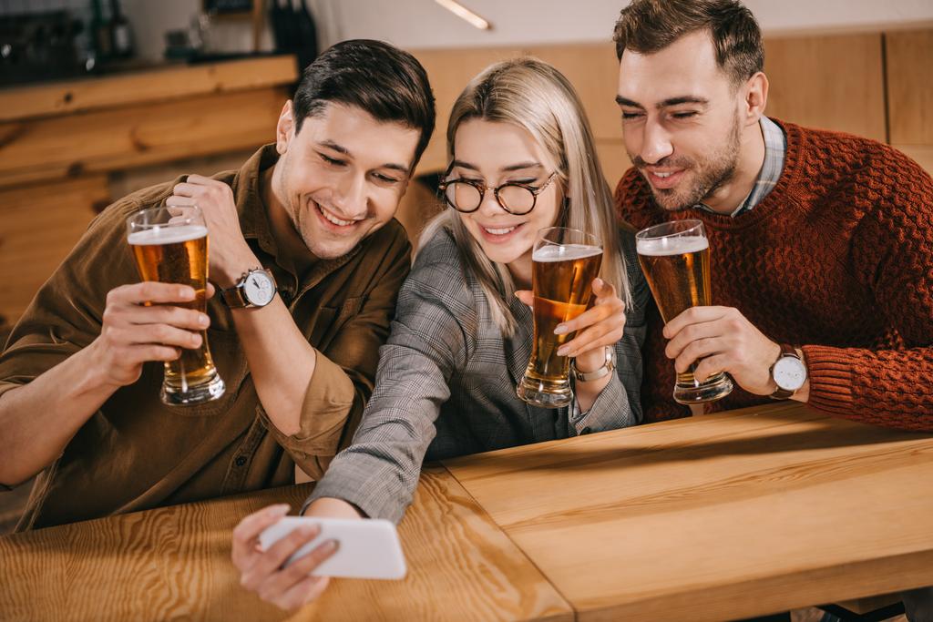 Selfie erkek arkadaş grubu alarak ve bardak bira tutan güzel kadın - Fotoğraf, Görsel
