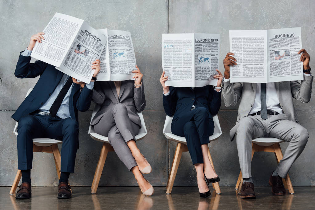 Geschäftsleute sitzen auf Stühlen und halten Zeitungen vor die Gesichter in der Wartehalle - Foto, Bild