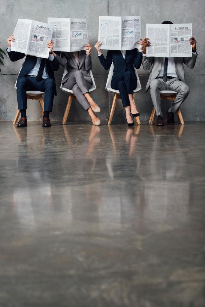 Des gens d'affaires assis sur des chaises et tenant des journaux devant des visages dans la salle d'attente avec espace de copie
 - Photo, image