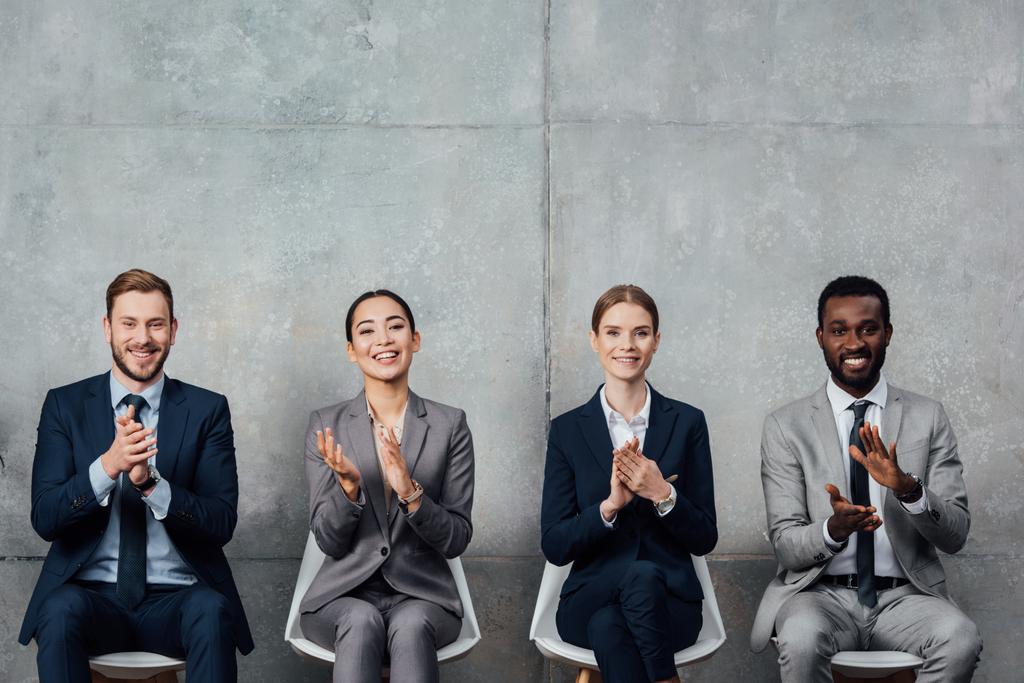 empresários multiétnicos sentados em cadeiras e aplaudindo na sala de espera
 - Foto, Imagem