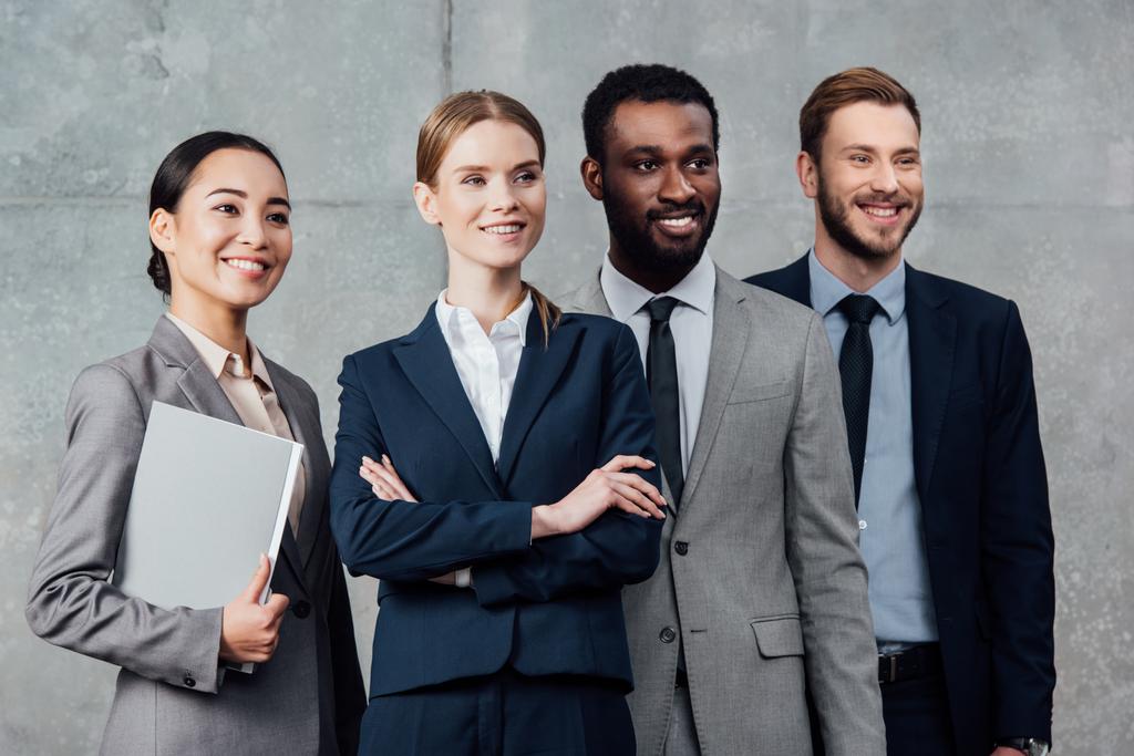 lächelnde multiethnische Gruppe von Geschäftsleuten in formeller Kleidung posiert und schaut weg - Foto, Bild