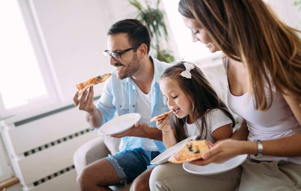 Портрет счастливой семьи, делящей пиццу дома
 - Фото, изображение