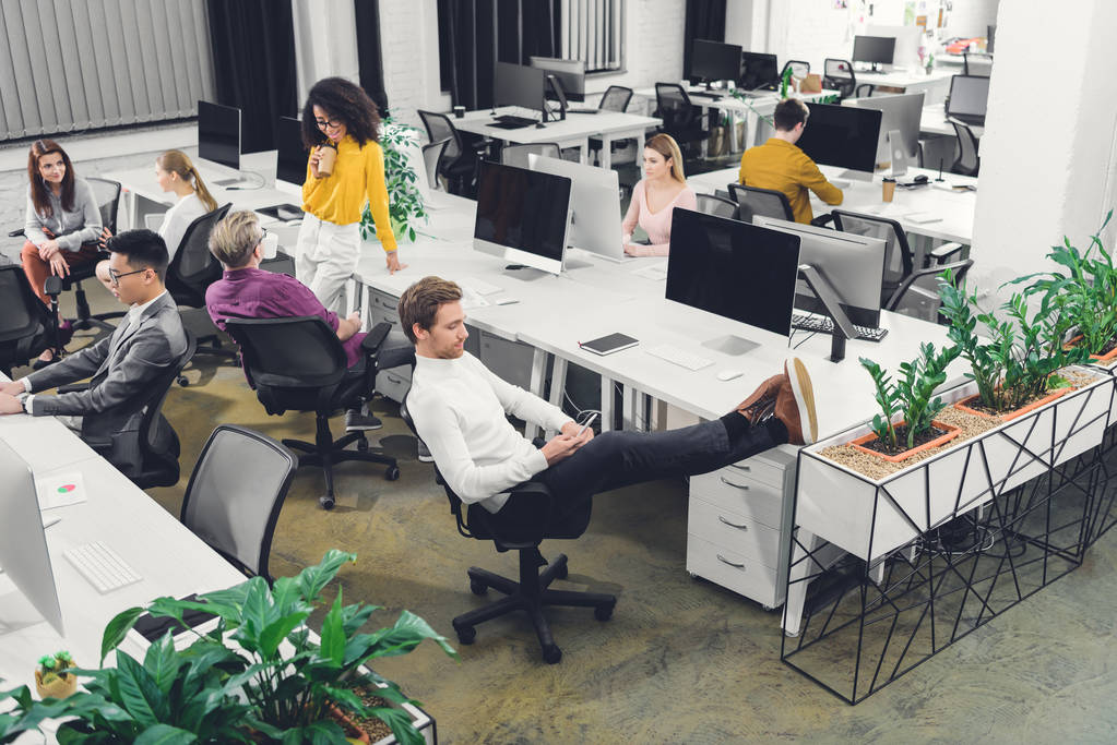 hoge hoekmening van jonge collega's praten en werken in open ruimte kantoor  - Foto, afbeelding