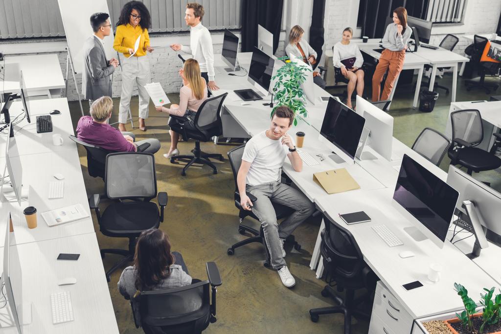 високий кут зору професійних молодих бізнесменів, які працюють з паперами та комп'ютерами у відкритому космосі
   - Фото, зображення