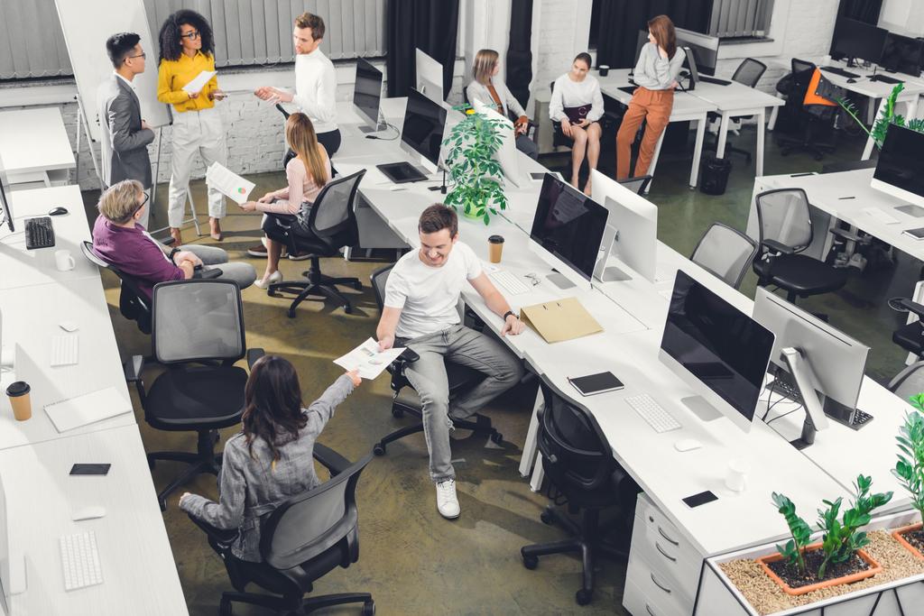 vue en grand angle de jeunes collègues professionnels travaillant avec des papiers et des ordinateurs dans un bureau à aire ouverte
  - Photo, image
