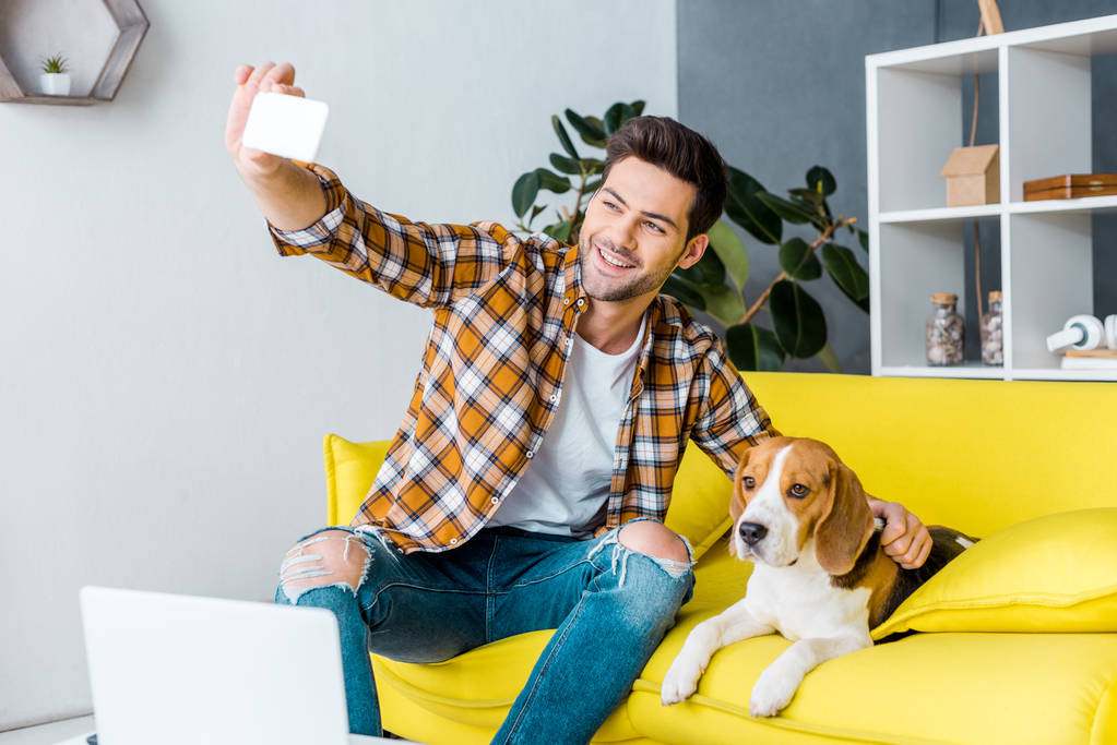 krásný usměvavý muž vezme selfie s pes beagle - Fotografie, Obrázek