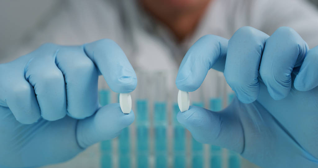 Ritratto di uno scienziato che tiene e mostra un paio di pillole in un laboratorio. Concetto: chimica, laboratorio, scienza
. - Foto, immagini