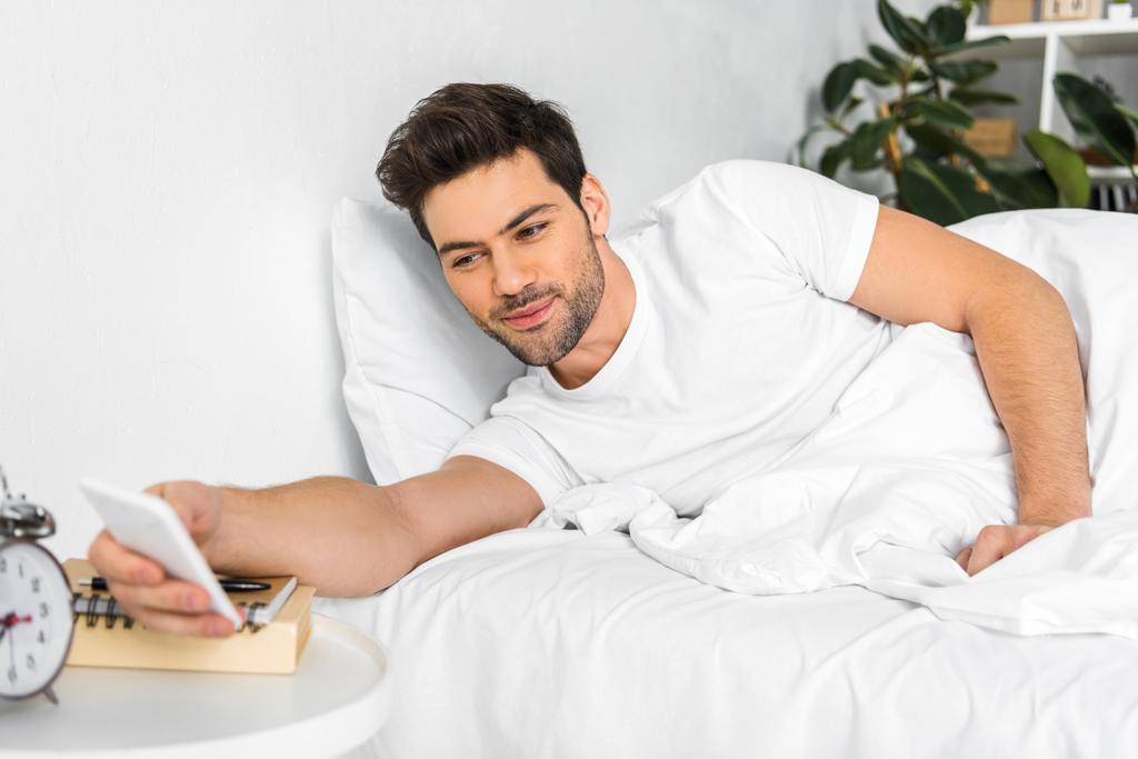 ευτυχισμένος άνθρωπος ξυπνήσει και κοιτάζοντας smartphone το πρωί - Φωτογραφία, εικόνα
