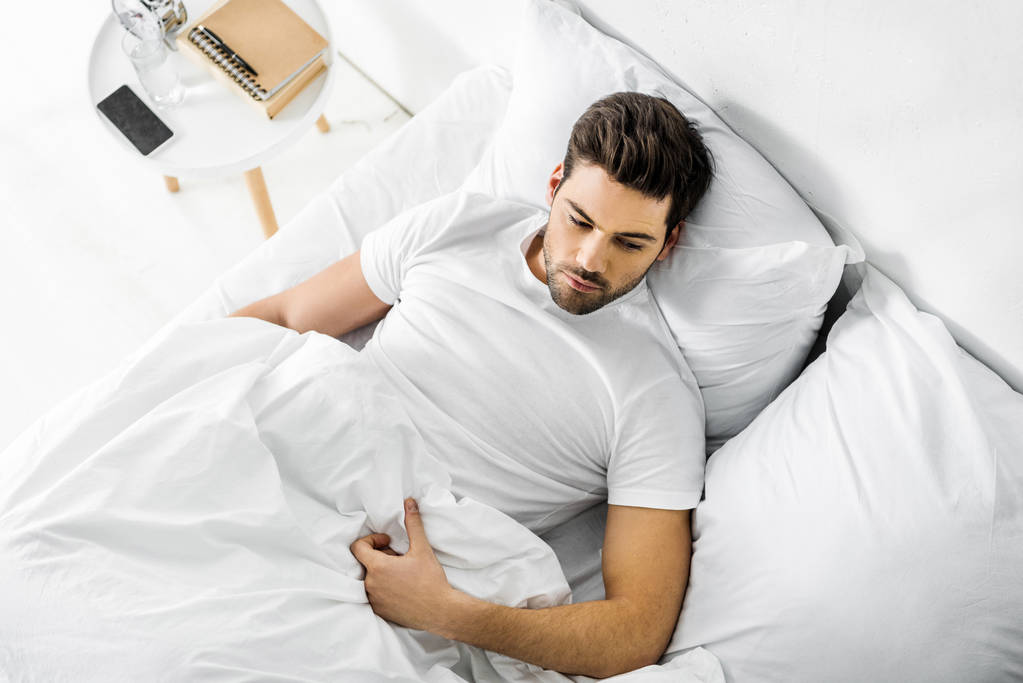 pohled shora pohledný muž odpočívá v posteli ráno - Fotografie, Obrázek