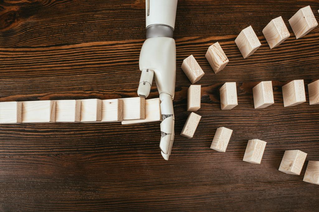 pohled shora robotické ruky brání pádu na stole dřevěných kostek - Fotografie, Obrázek