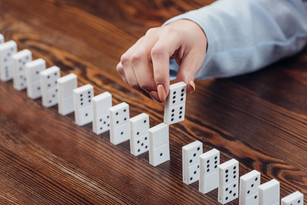 cropped view of woman picking domino from row on wooden desk - Photo, Image