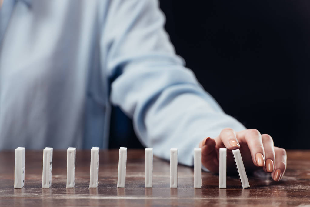Ausgeschnittene Ansicht einer Frau, die Domino-Reihe auf Holztisch schiebt - Foto, Bild