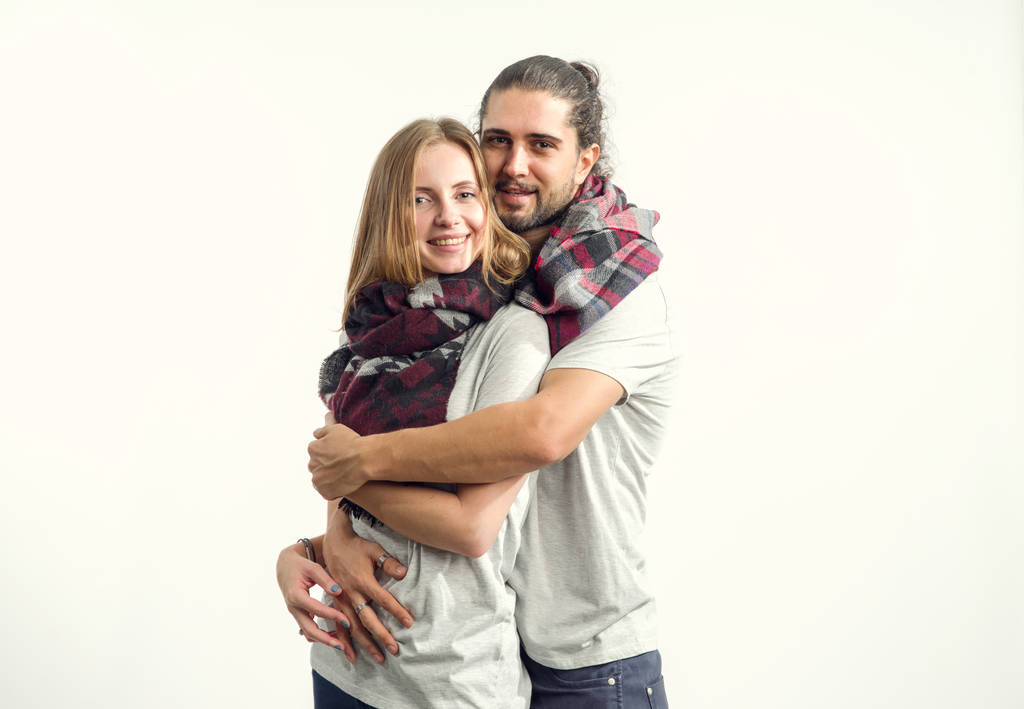 Jong koppel in liefde in shirts en sjaals staande op een lichte achtergrond. Man en vrouw. - Foto, afbeelding