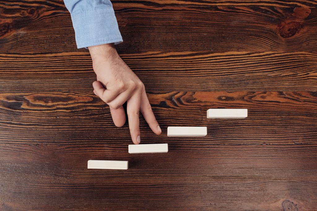 cropped view of man walking with fingers on wooden blocks symbolizing career ladder  - Photo, Image
