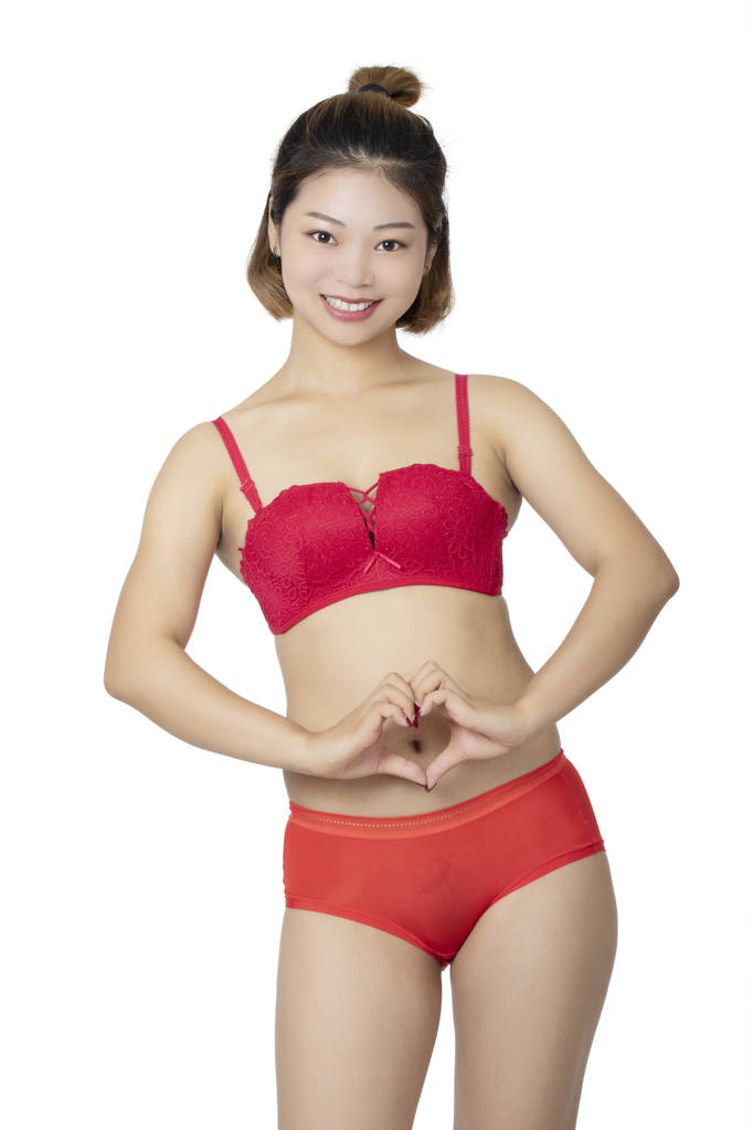 Kaunis kiinalainen nainen poseeraa pari punaiset pikkuhousut ja rintaliivit eristetty valkoisella taustalla
. - Valokuva, kuva